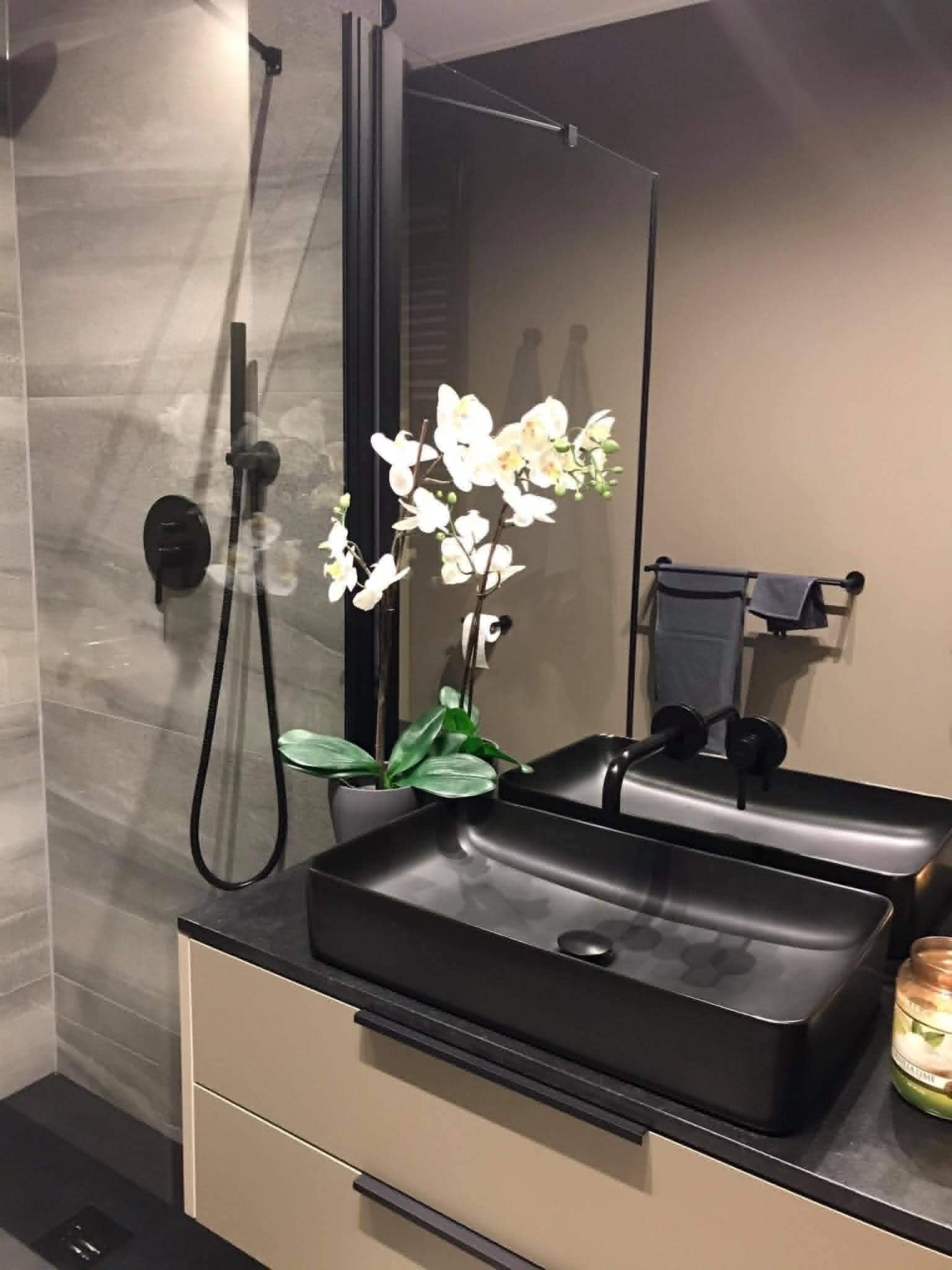 Black countertop basin with black wall-mounted tap and shower detail